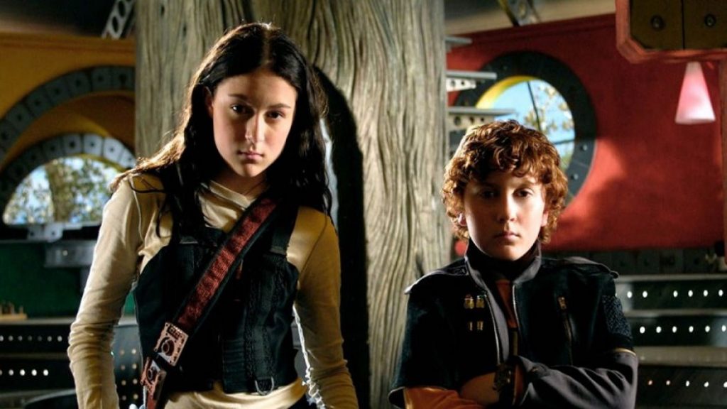 The siblings from Spy Kids, Carmen and Juni, stand confidently while outfitted for some serious spy business.
