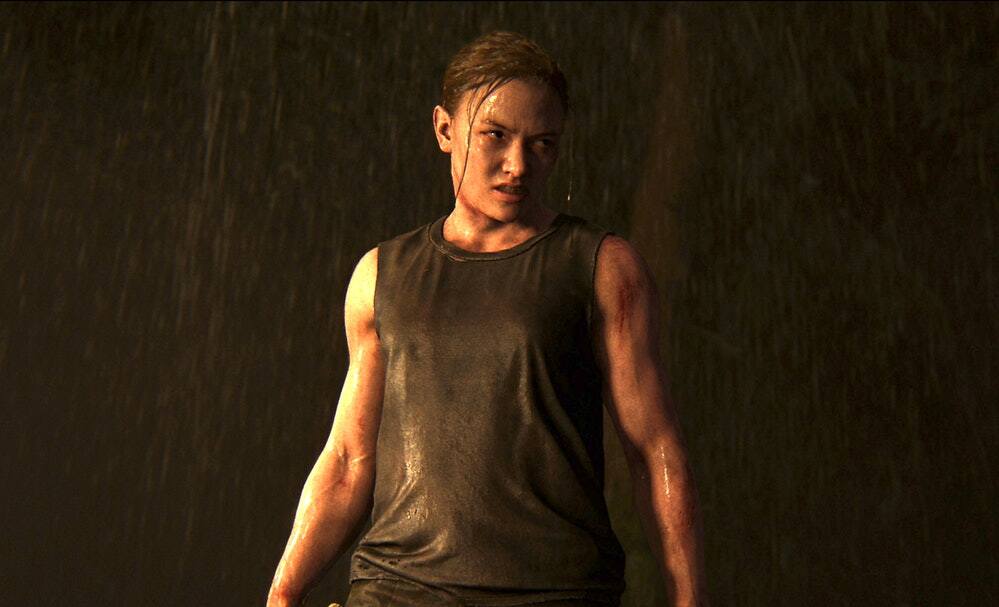 A buff woman from The Last of Us II stands in a downpour, hatred on her face. Blood smears her muscled arms.
